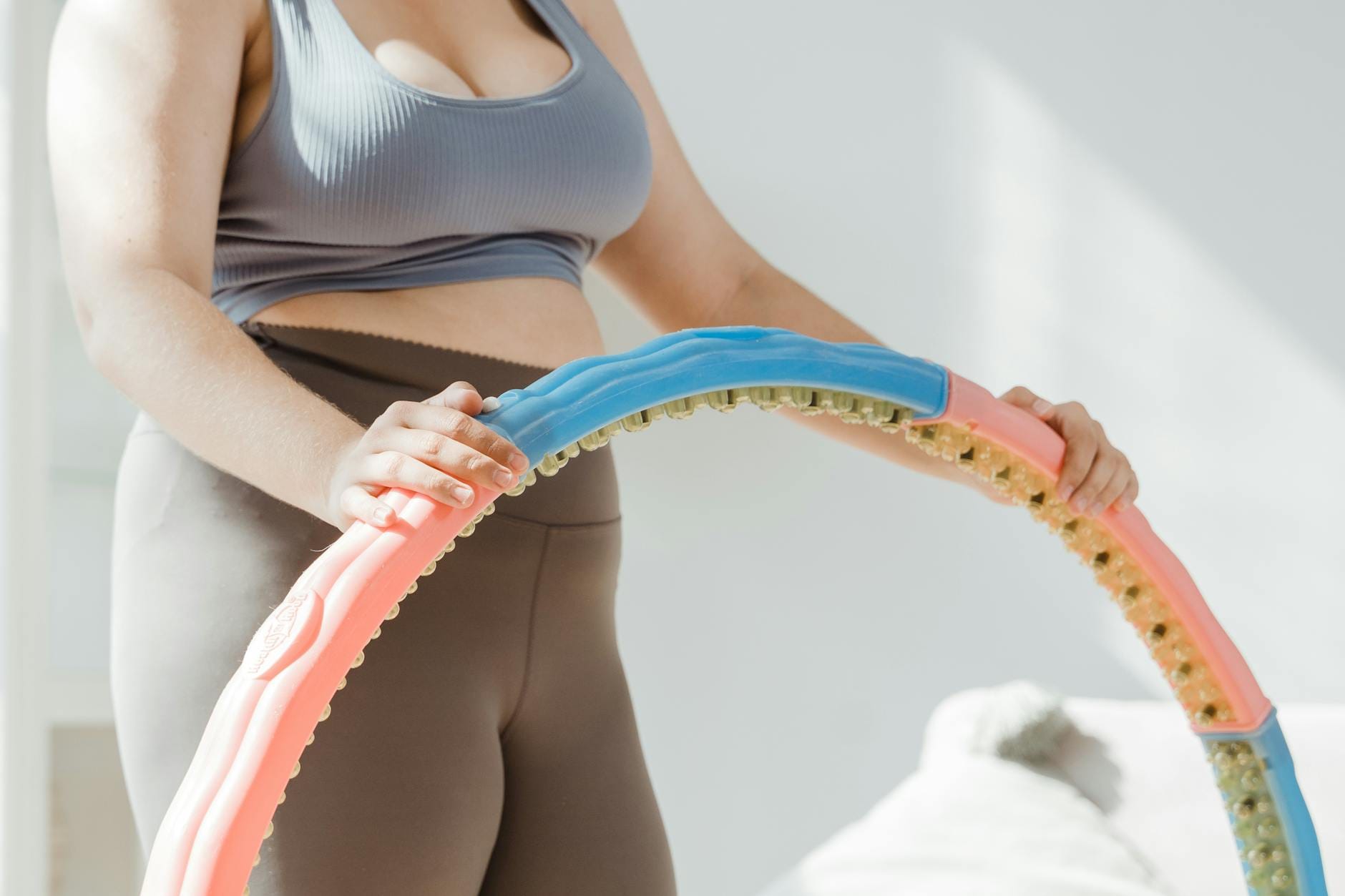 Kobieta w stroju sportowym ćwiczy w salonie z kolorowym hula hop