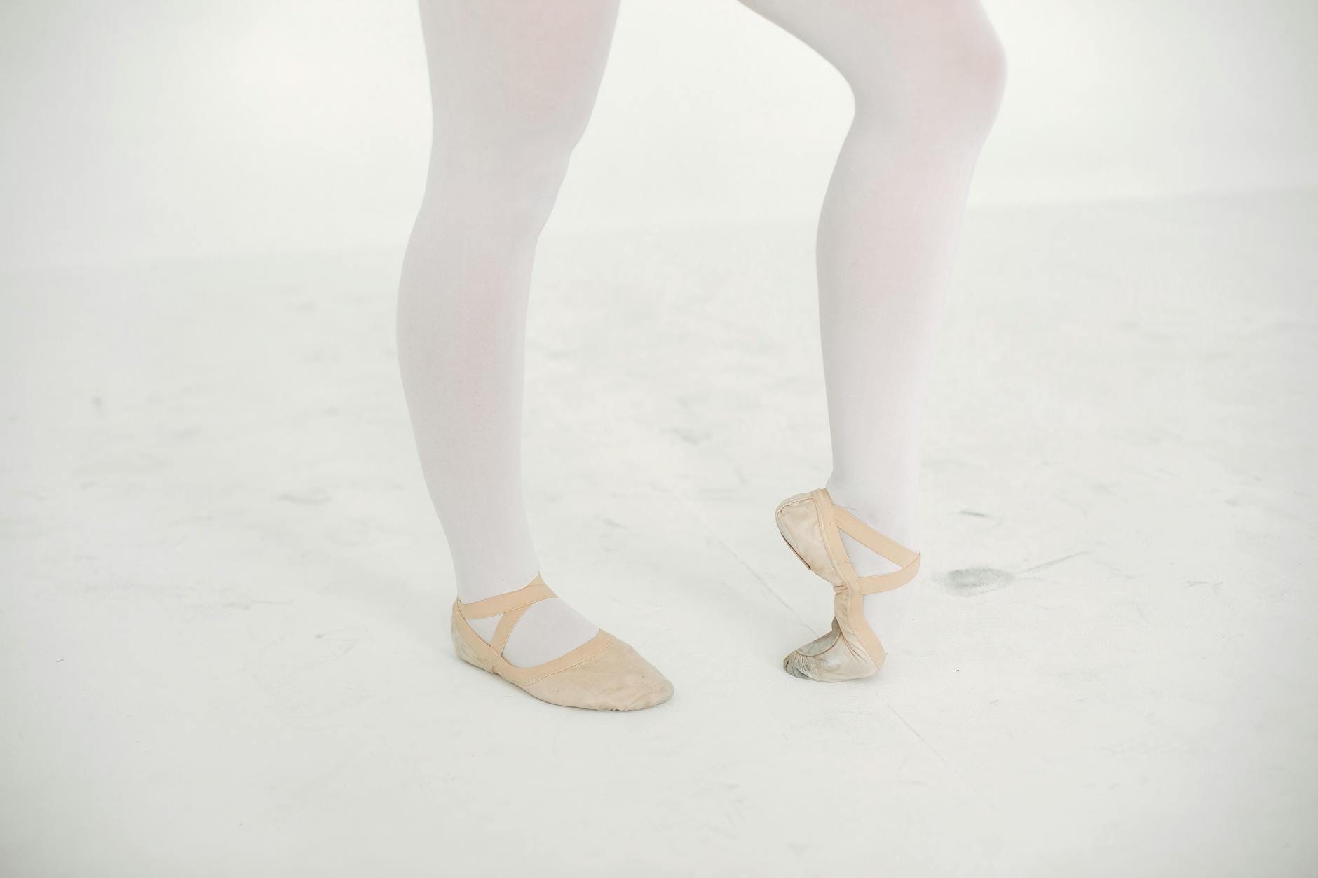 Stopy baletnicy w pointach na białym tle, przykład przeciążeń stóp