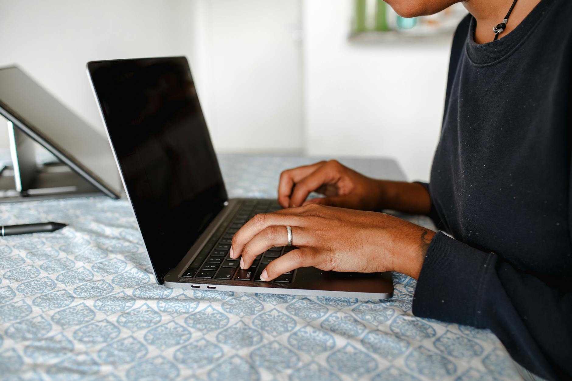 Dorosła osoba pisząca na laptopie w przytulnym pomieszczeniu