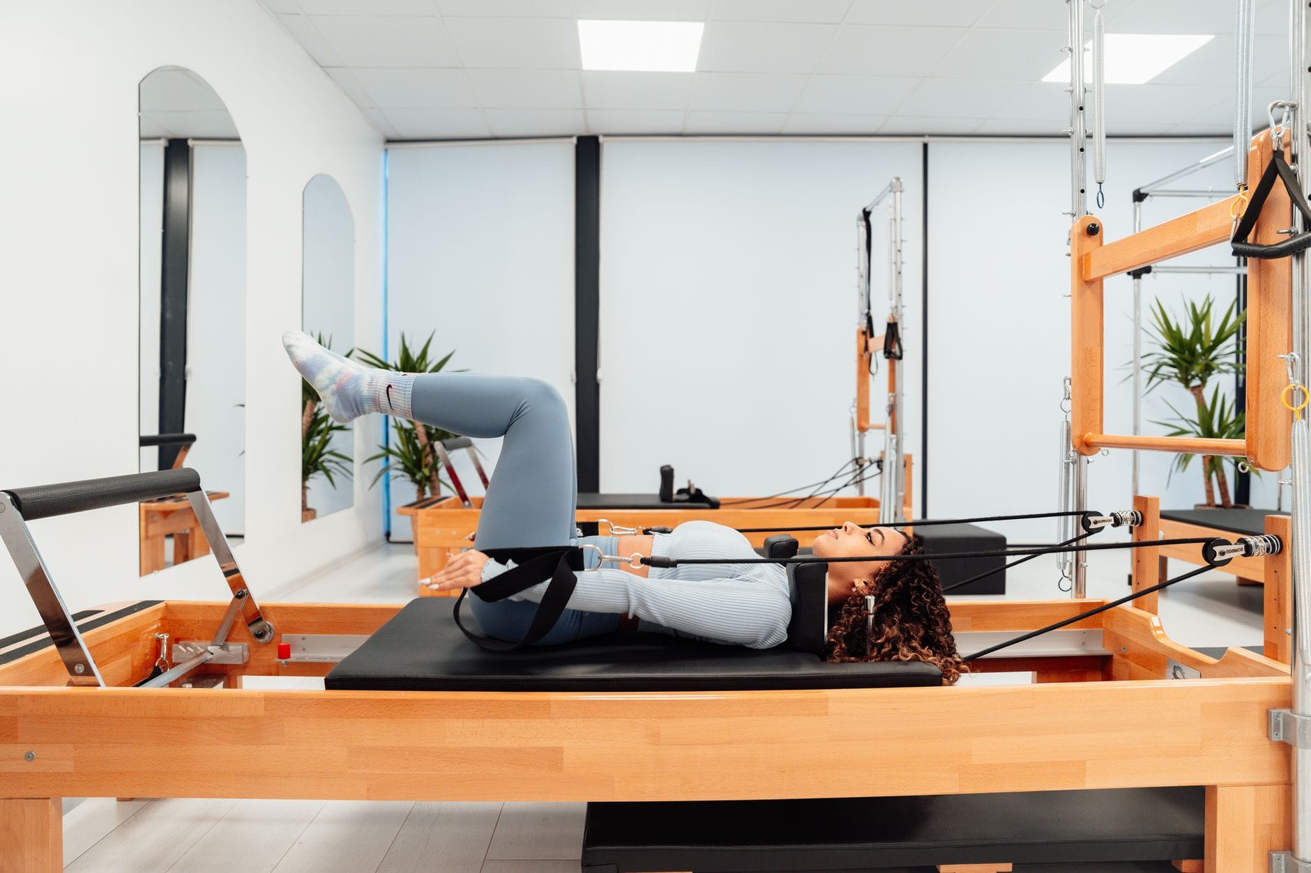 Kobieta ćwiczy pośladki na reformerze Pilates w nowoczesnej siłowni