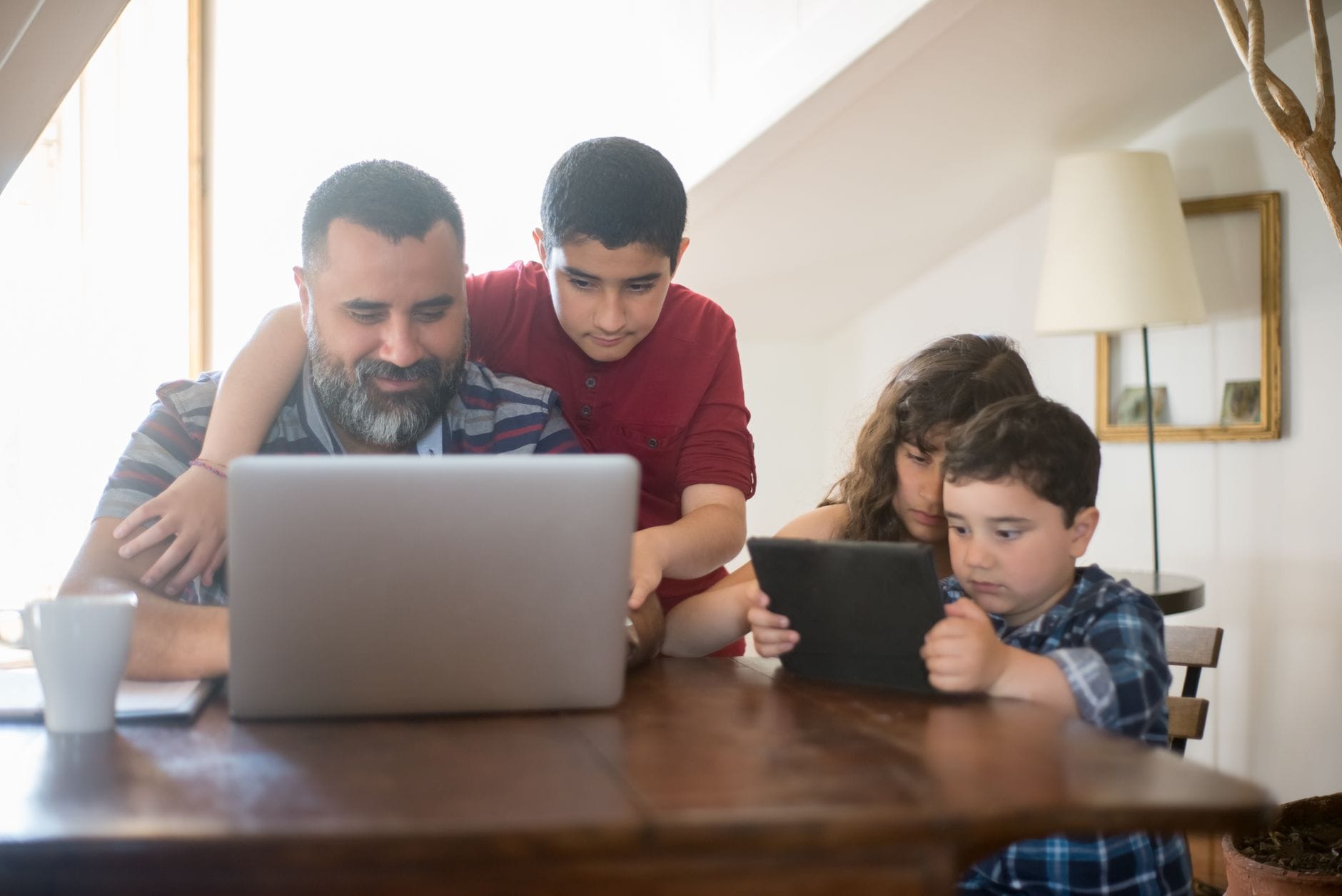 Ojciec z dziećmi uczy się obsługi AI na laptopie i tablecie w domu