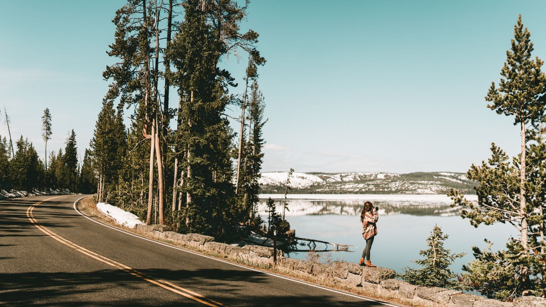 Kobieta fotografuje zimowy krajobraz nad jeziorem Yellowstone i górami Kobieta fotografuje zimowy krajobraz nad jeziorem Yellowstone i górami